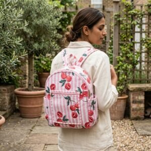 Close-up of the handcrafted pink cherry botanical print detailing, dense quilted stitching texture lines, robust adjustable shoulder straps, and spacious open interior layout on an Indian cotton travel daypack.