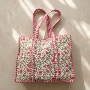 Close-up of the handcrafted pink botanical print detailing, dense quilted stitching texture lines, robust handle strap attachments, and clean inner layout on an Indian cotton travel purse.