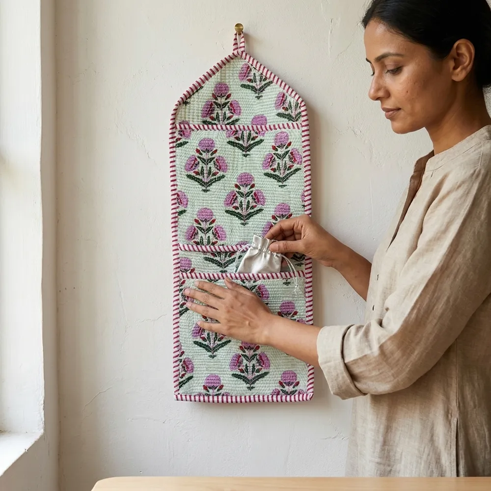 Pink Floral Quilted Wall Hanging Organizer displaying the multi-pocket vertical sorting slots with the traditional blush floral print artisan design hung securely on an entryway wall.