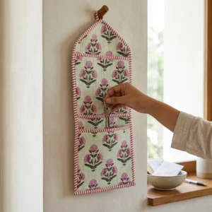 An interior room setup showing the Pink Floral Quilted Wall Hanging Organizer near a wooden office desk, showcasing its space-saving capacity and elegant patterned office home pocketbook style.