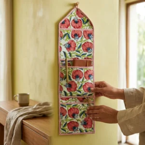 An interior room setup showing the Pink Floral Quilted Wall Hanging Organizer near a wooden office desk, showcasing its space-saving capacity and elegant patterned office home pocketbook style.