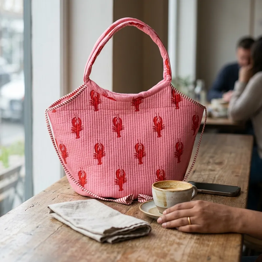 Close-up of the handcrafted pink coastal lobster print detailing, dense quilted tracking lines, clean magnetic snap button, and interior slip pocket on the cotton handbag.