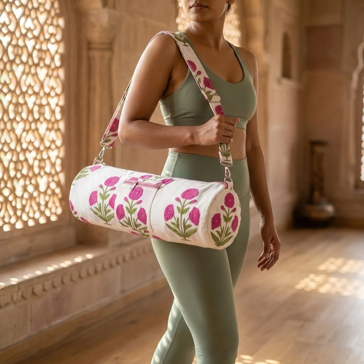 An outdoor studio scene featuring the Pink Poppy Quilted Cotton Yoga Mat Bag draped across a person's shoulder, highlighting its lightweight hands-free carrying convenience and bohemian style.