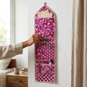 An interior room setup showing the Purple Fabric Wall Hanging Organizer near a wooden desk, showcasing its space-saving capacity and elegant magenta patchwork decor holder style.