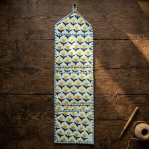 Close-up of the handcrafted yellow botanical blossom print detailing, soft quilted construction lines, heavy-duty stitching borders, and clean empty pocket entry slot on an Indian cotton wall organizer.