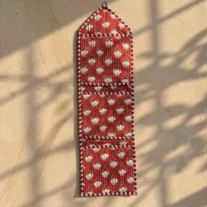 Close-up of the handcrafted red botanical print detailing, dense quilted stitching texture lines, robust pocket seam attachments, and clean pocket opening on the cotton pocket storage.