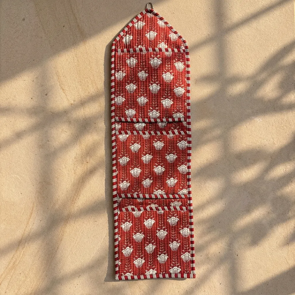 Close-up of the handcrafted red botanical print detailing, dense quilted stitching texture lines, robust pocket seam attachments, and clean pocket opening on the cotton pocket storage.