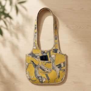 Close-up of the handcrafted yellow cat print detailing, dense quilted stitching texture lines, robust handle strap attachments, and clean inner layout on an Indian cotton market purse.