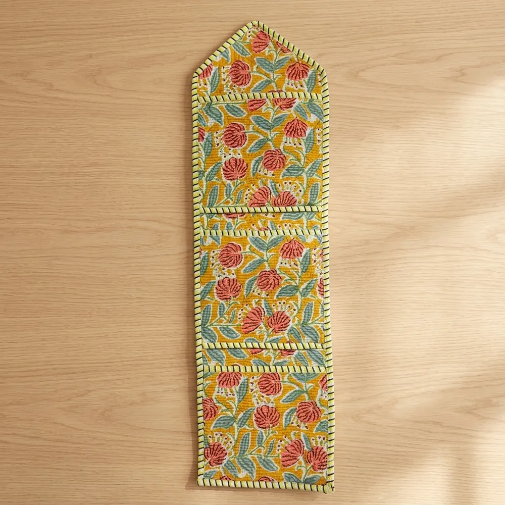 Close-up of the handcrafted yellow botanical print detailing, dense quilted stitching texture lines, robust pocket seam attachments, and clean pocket opening on the cotton pocket storage.