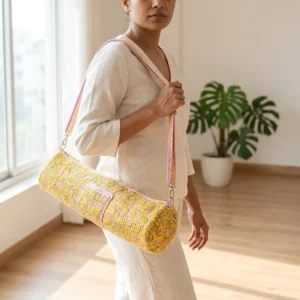 An outdoor studio scene featuring the Yellow Floral Quilted Cotton Yoga Mat Bag draped across a person's shoulder, highlighting its lightweight hands-free carrying convenience and bohemian style.