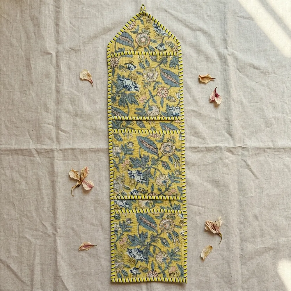 Close-up of the handcrafted yellow botanical print detailing, dense quilted stitching texture lines, robust pocket seam attachments, and clean pocket opening on the cotton pocket storage.