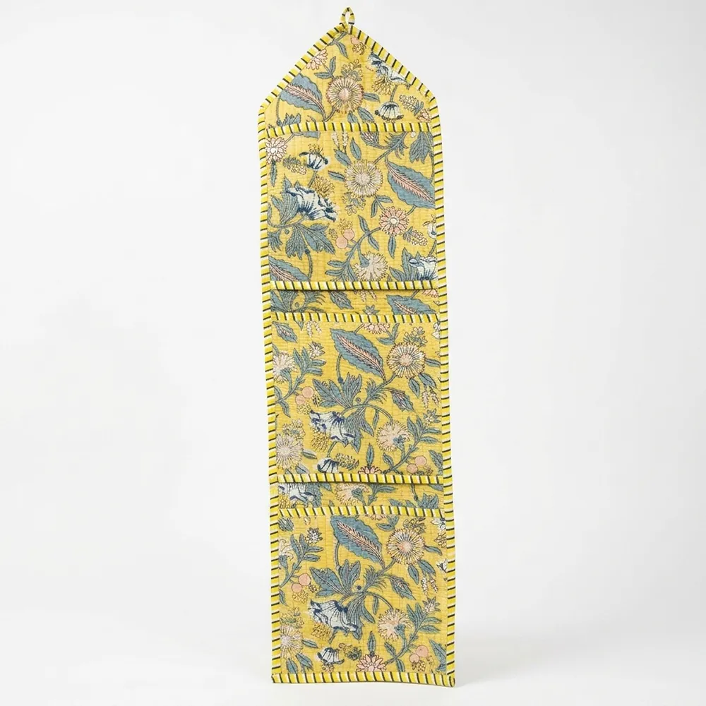 Close-up of the handcrafted yellow botanical print detailing, dense quilted stitching texture lines, robust pocket seam attachments, and clean pocket opening on the cotton pocket storage.
