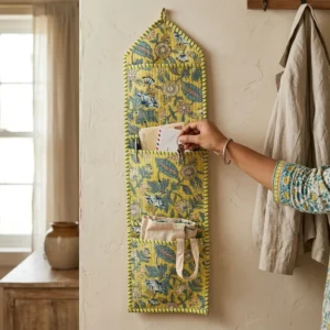 An interior room setup showing the Yellow Floral Quilted Wall Hanging Organizer near a wooden desk, showcasing its space-saving capacity and elegant mustard decor holder style.