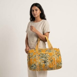 A traveler carrying the Yellow Safari Quilted Cotton Duffel Bag by the wide handles, showcasing its generous packing capacity and elegant bohemian accessory style while boarding a flight.