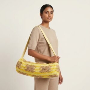 A fitness enthusiast carrying the Yellow Tiger Print Yoga Mat Bag over the shoulder by the wide straps, showcasing its long profile and classic bohemian accessory style while heading to a yoga studio class.