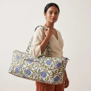 An outdoor studio scene featuring the Blue Marigold Quilted Cotton Yoga Mat Bag held by its shoulder straps, highlighting its lightweight carrying convenience and bohemian style.