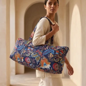 An outdoor studio scene featuring the Quilted Cotton Yoga Mat Bag held by its shoulder straps, highlighting its lightweight carrying convenience and bohemian style.